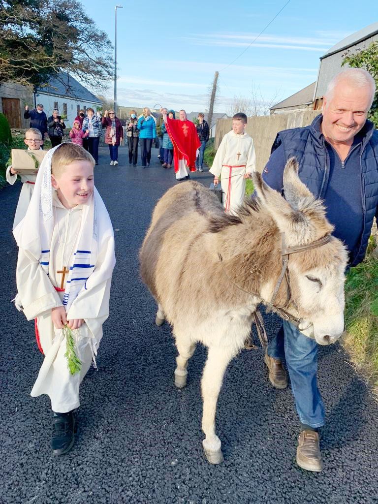 Child, adult, donkey in outdoor Palm Sunday procession